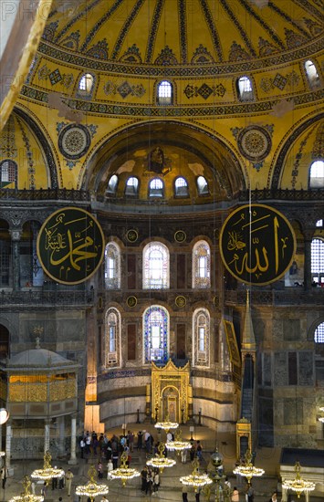 Turkey, Istanbul, Sultanahmet Haghia Sophia Sightseeing tourists beneath the dome with murals and chandeliers in the Nave of the Cathedral with calligraphic roundels of Arabic Koran texts above the Lodge of The Sultan. 
Photo : Paul Seheult