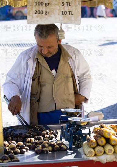Turkey, Istanbul, Sultanahmet Man selling roast chestnuts and sweetcorn in the street. 
Photo : Paul Seheult