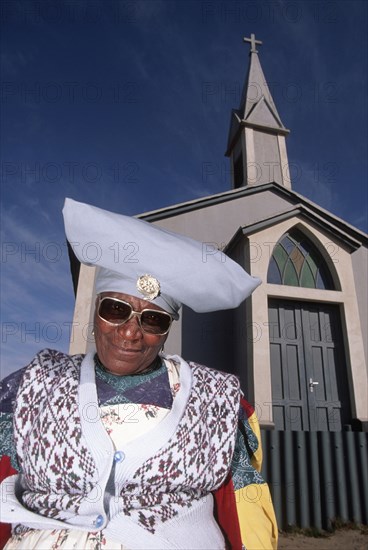 Namibia, Mondesa, Herero woman in Mondesa the township of Walvis Bay Namibia standing next to a Presbytarian church. 
Photo : Adrian Arbib