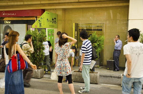 Japan, Honshu, Tokyo, Ginza district smokers using designated street smoking area. 
Photo : Jon Burbank