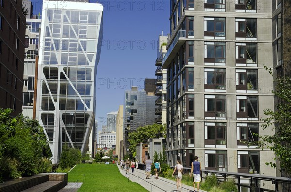 USA, New York, Manhattan, West Side Highline Park at 23th Street the HL23 Building on the left projecting over the park with people strolling. 
Photo : Jon Burbank