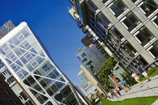 USA, New York, Manhattan, West Side Highline Park at 23th Street the HL23 Building on the left projecting over the park with people strolling. 
Photo : Jon Burbank