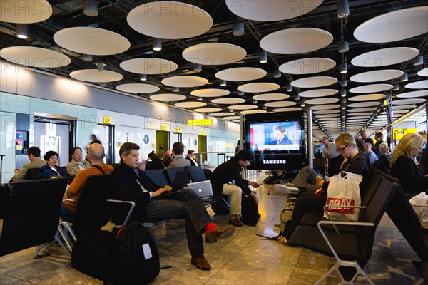 England, London, Heathrow Airport Terminal 5 disc ceiling in departures zone with passengers waiting in seating area at gate. 
Photo : Paul Seheult