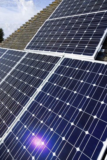 Architecture, Environment, Solar Panels, Alternative Energy Electricity Solar photovoltaic roof panels on detached house for electricity conversion with the sun reflected in a panel. 
Photo : Paul Seheult