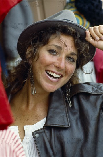 Smiling teen girl wearing hat and leather jacket.