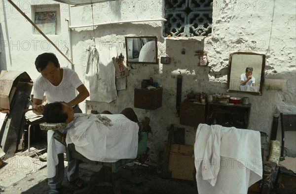 Georgetown man having a shave from a street barber.