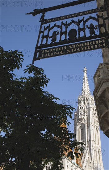 Buda Castle District: Matyas Church viewed from wrought iron traditional shop sign.