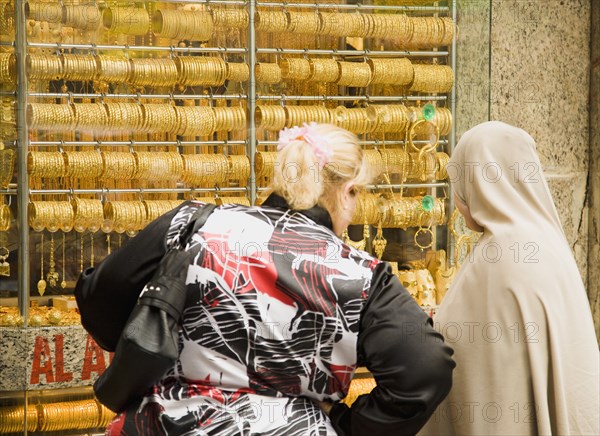 Women one veiled shop for gold jewellery in window display of Gold Souk Deira.