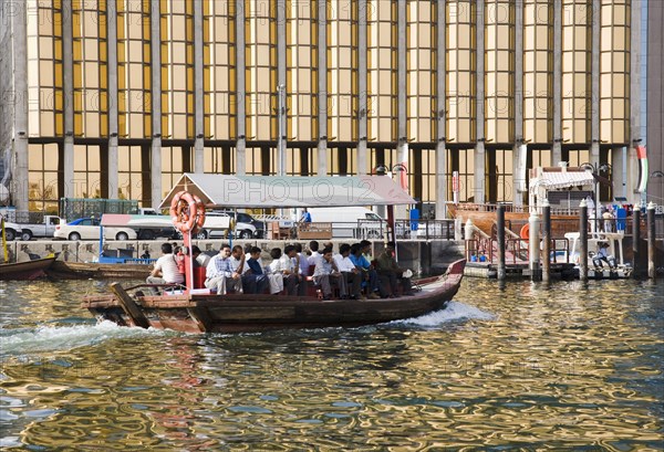 Abra water taxi taking commuters across the Creek with bank facade behind.