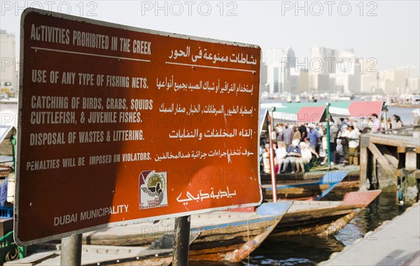 Municipal sign showing rules and penalties on the Creek with skyline behind.