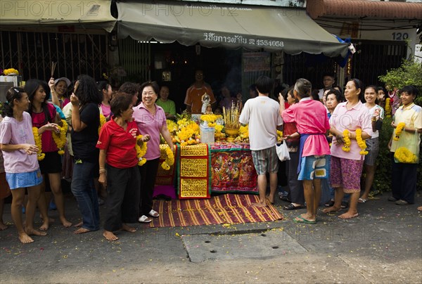 Women in front of Guanyin female Goddess of Mercy statue with offerings for parade celebrating local temple.