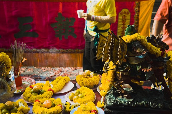 Offerings on table with embroidered panel behind carried in parade celebrating local temple.