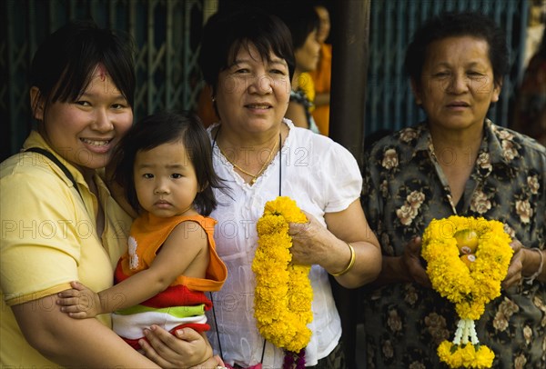 Four female generations of family with floral garlands to celebrate the annual blessing of local temple.