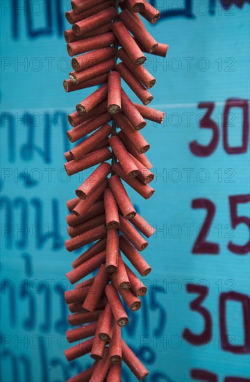 Firecrackers celebrating local temple in front of Thai script on menu board