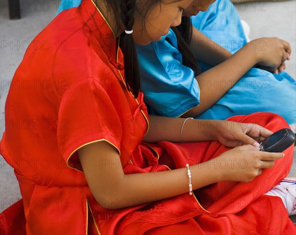 Thai girls using mobile telephone in costume of dance troupe.