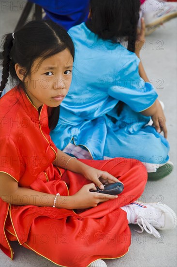 Thai girls using mobile telephone in costume of dance troupe.