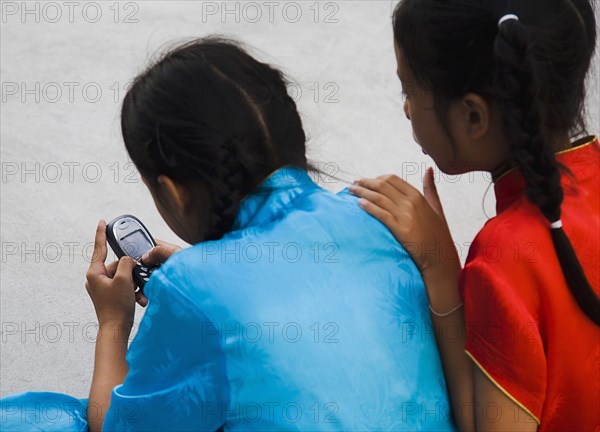 Thai girls using mobile telephone wearing costume of dance troupe.
