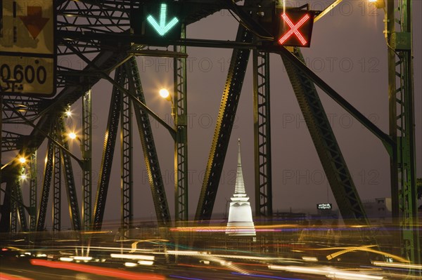 Traffic flow control in evening rush hour on Saphan Phut Memorial Bridge illuminated Stemple mstup in the background.