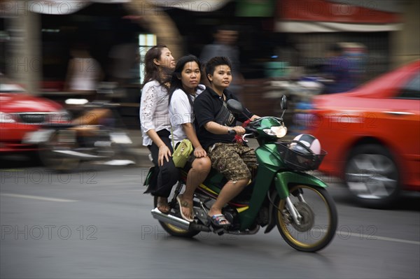 Young Thai women on motorcycle without helmets helmet in shopping basket blurred motion.