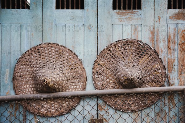 Vintage conical straw hats displayed on wall.