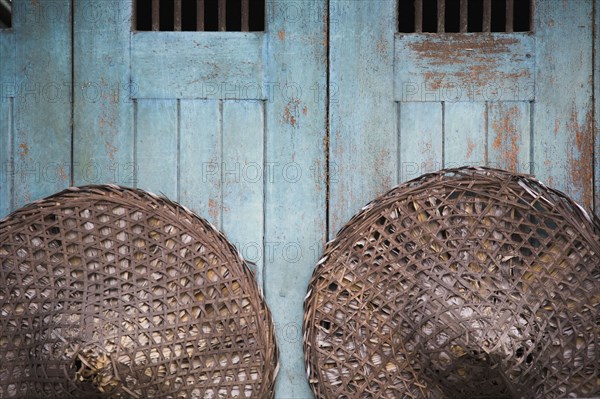 Vintage conical straw hats displayed on wall.