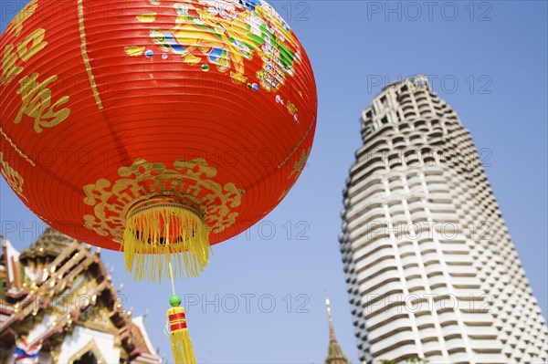 Wat Yannawa temple roof and unfinished apartment block from 1990s Asian financial crash with red lanterns at Chinese New Year.