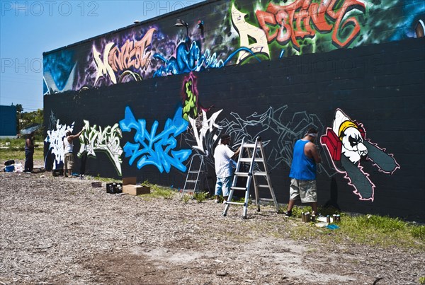 Graffiti artists painting wall.
