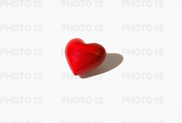 Studio shot of a single red coloured heart shaped stone.