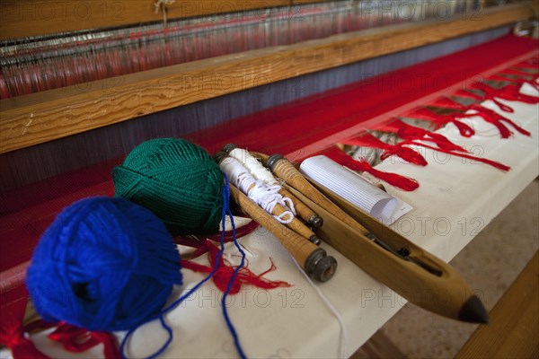 Close of an old traditional loom with balls of wool and tools.