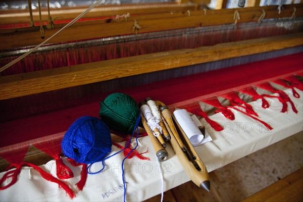 Close of an old traditional loom with balls of wool and tools.