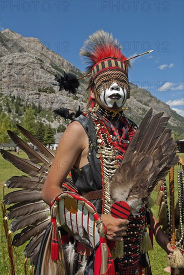 Blackfoot head dancer Aryson Black Plume in full regalia and face paint at the Blackfoot Arts & Heritage Festival Pow Wow organized by Parks Canada and the Blackfoot Canadian Cultural Society Headdress with arrow and black plume