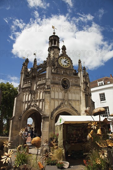 The Market Cross and a wooden craft market store in the foreground.