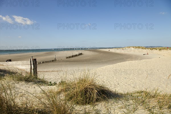 View across sand dunes towards beach and sea at East Head. Sunshine and blue sky.