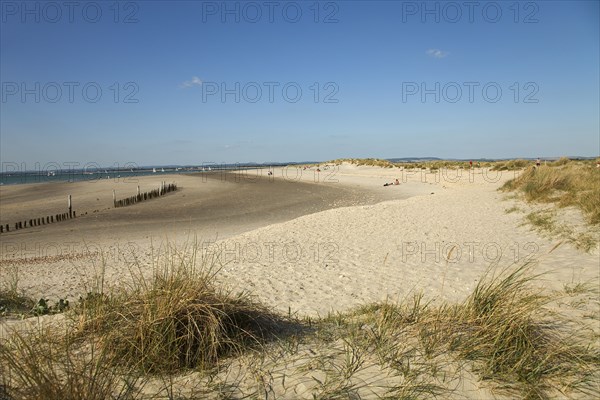 View across sand dunes towards beach and sea at East Head. Sunshine and blue sky.