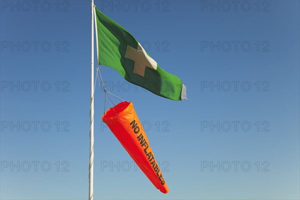 Safety flags. White Cross on Green Flag signalling First Aid Point. Orange No Inflatables windsock.