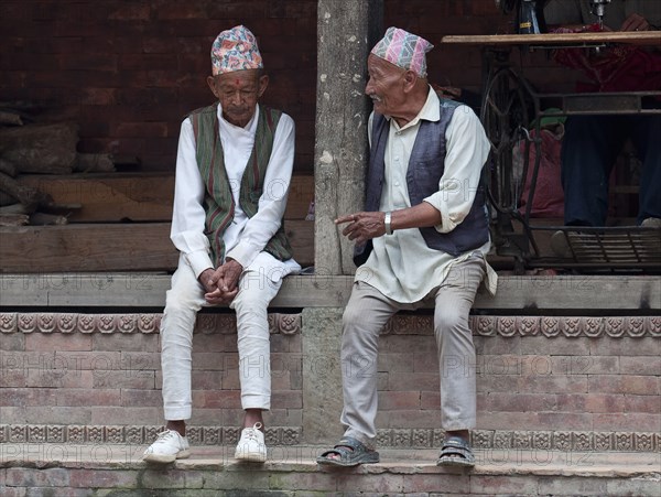 Two older men in national clothes are talking.