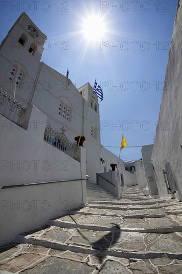 Portrait format low angle photograph of a typical alley found only at Cyclades island complex with the church of Agios Spyridonas on the left hand side.