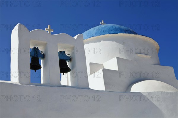 Traditional small white church with a blue dome white crosses and old copper made bells.