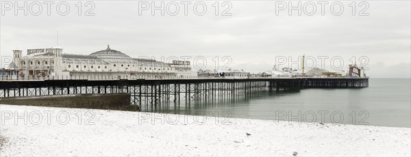 Pier during winter with snow on the beach.