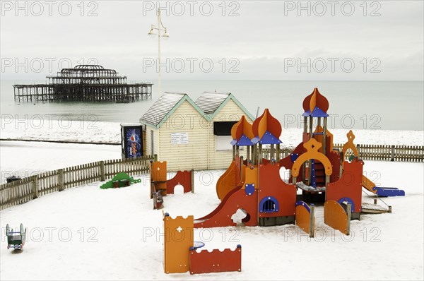 West Pier during winter with snow on the beach and childrens play area in the foreground.