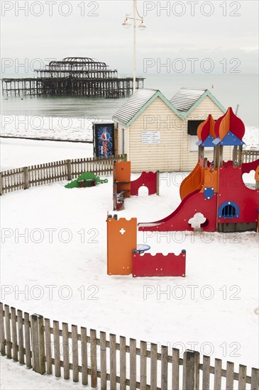 West Pier during winter with snow on the beach and childrens play area in the foreground.