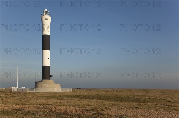 Black and white painted lighthouse on the shingle beach.