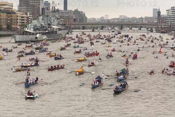 Flotilla of small rowing boats proceed along River Thames past HMS Belfast as part of the Queens Thames Diamond Jubilee Pageant taken from Tower Bridge 3rd June 2012.