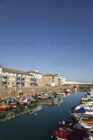 View over boats moored in the Marina with apartment buildings behind.