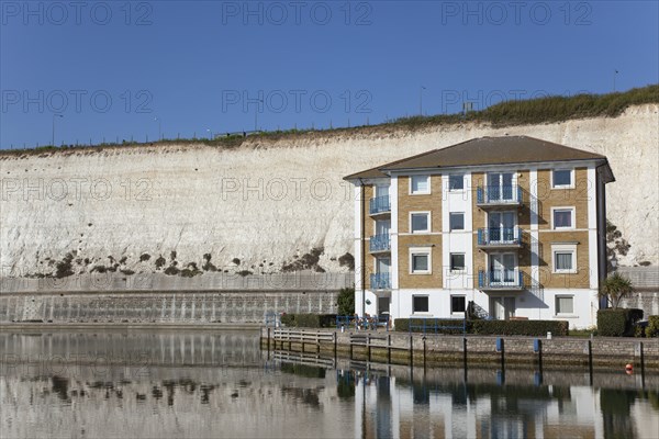 Apartment building in empty marina with chalk cliffs behind.