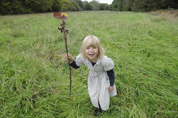 5 year old Eva with stick & leaf flag in a field of grass.