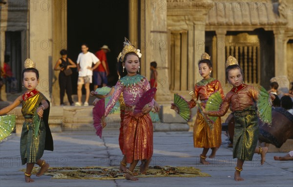 Cambodia, Angkor, Angkor Wat, Child dancers in traditional dress with tourists framed by temple entrance behind. Photo : William Holtby