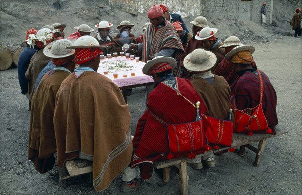 Bolivia, La Paz, Amarete, Fiesta de San Felipe held on May 1st. Group of men sat around table being served hot drink. Photo : Eric Lawrie