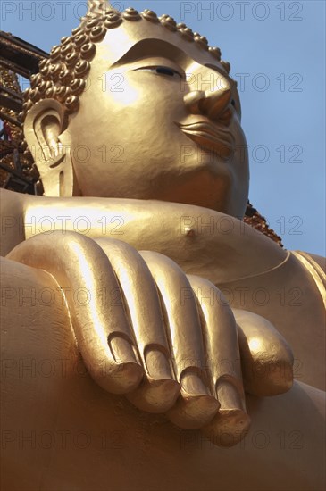 Thailand, Religion, Buddhism, Angled view of large golden seated Buddha statue. Photo : Derek Cattani