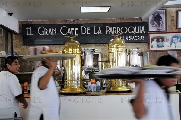 Mexico, Veracruz, Cafe El Gran Cafe de la Parroquia interior with waiters carrying laden trays past bar area. Photo : Nick Bonetti